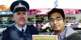 Officer Mal Drummond and Victory Square’s On the Spot dairy manager Veer Savniya with one of the campaign posters police have been handing out. Photo: Andrew Board.