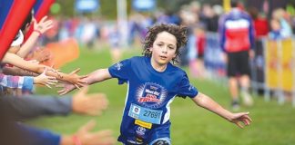 Spectators reach out to congratulate Ollie Walker as he finishes the Weet-Bix Kids Tryathlon on Sunday morning. Photo: Phillip Rollo.