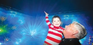 Kelvin Sparks helps his grandson Luke Foord, 7, reach up to the light beams coming off a display at Light Nelson on Sunday. Photo: Phillip Rollo.