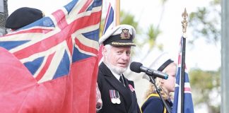 Retired captain Tom Rowling looks at a “Red Duster”, a Merchant Navy flag, during the Merchant Navy Parade at Anzac Park on Saturday morning. Photo: Andrew Board.